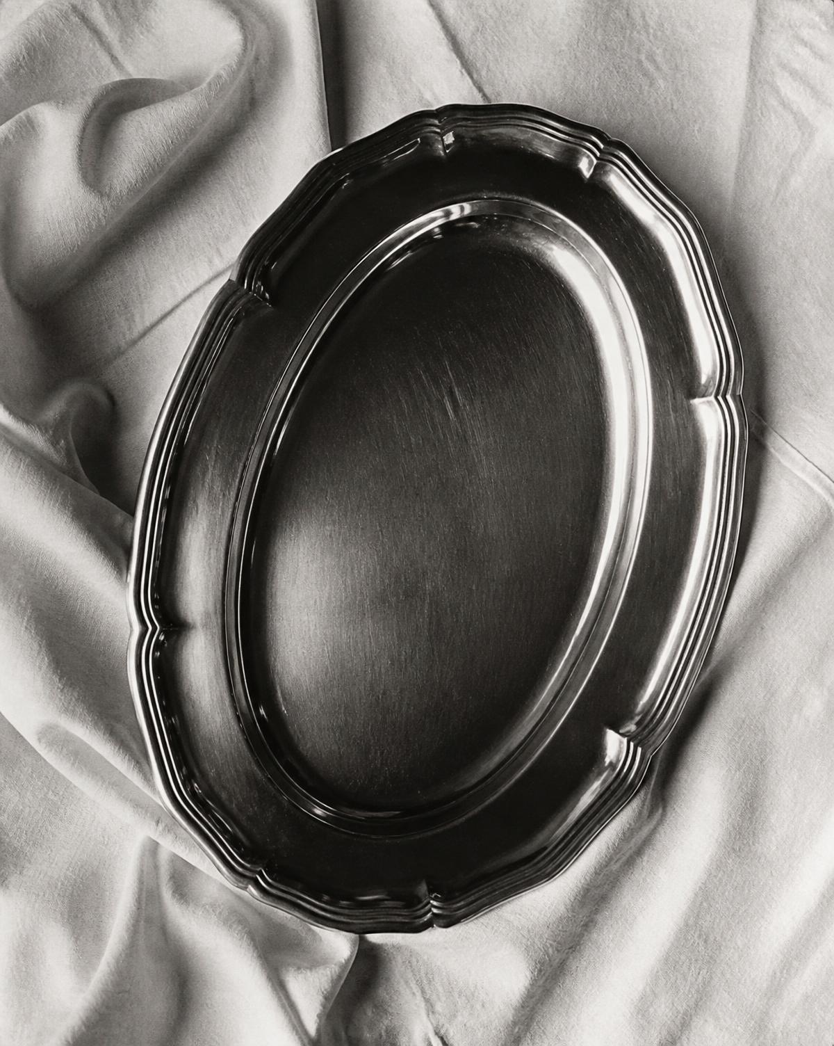 Black and white still life of a silver serving platter on linen
